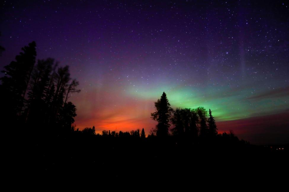 The wildfires glow underneath The Northern Lights, also known as the Aurora Borealis, near Fort McMurray