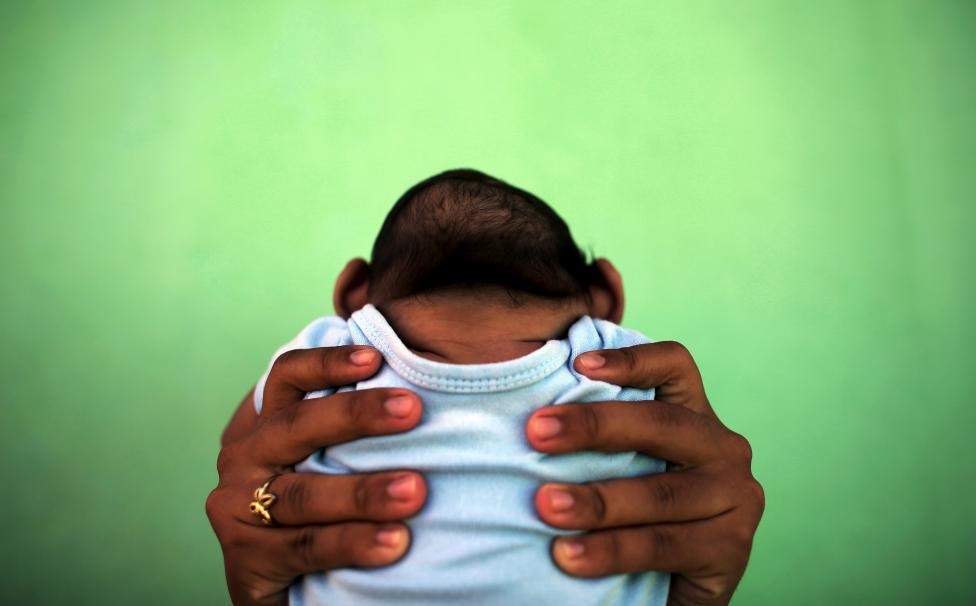 Jackeline, 26, holds her son who is 4-months old and born with microcephaly, in front of their house in Olinda, near Recife, Brazil, February 11, 2016. REUTERS/Nacho Doce